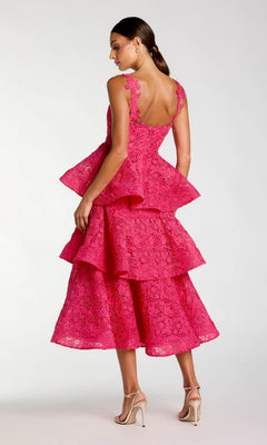 A woman stands in profile against a plain light background, wearing the Mac Duggal 56322 Midi Party Dress—a bright pink, sleeveless lace embroidered design with a low back—paired with beige high-heeled sandals.