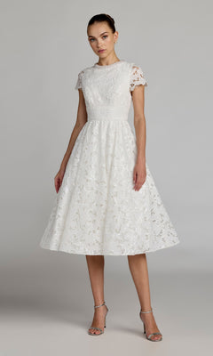 A woman wearing the Mac Duggal 56324 Midi Party Dress in ivory, featuring a fit-and-flare midi silhouette with short sleeves, styled with silver high-heeled sandals and standing against a plain background.