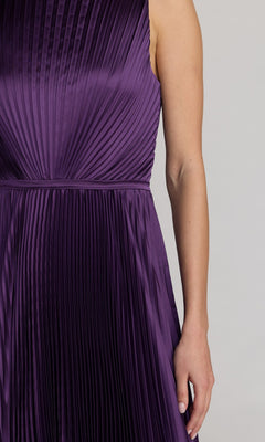 A person wearing the Mac Duggal 56326 Midi Party Dress, featuring a sleeveless design, pleated charmeuse fabric, and an elegant A-line skirt, stands with one arm relaxed by their side against a neutral background.