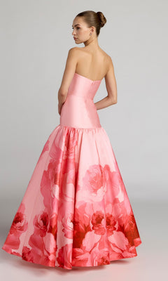A woman wears the Long Formal Dress: Mac Duggal 56343, featuring a strapless fitted Mikado drop waist bodice and a full, floral-patterned skirt, standing against a plain background. The elegant look is reminiscent of signature Mac Duggal designs.