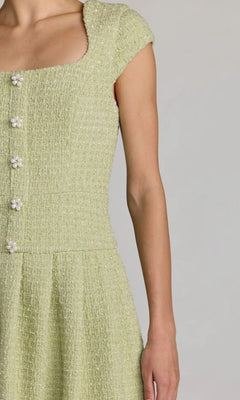 A person wearing the Mac Duggal 56373 Short Casual Dress in light green, featuring a textured boucle fabric and pearl button details, shown from shoulder to waist against a plain background.