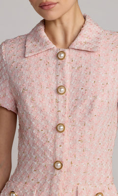 A close-up of a person wearing the Mac Duggal 56379 short party dress, featuring short sleeves, pink textured boucle fabric, a collar, and four pearl buttons down the front.