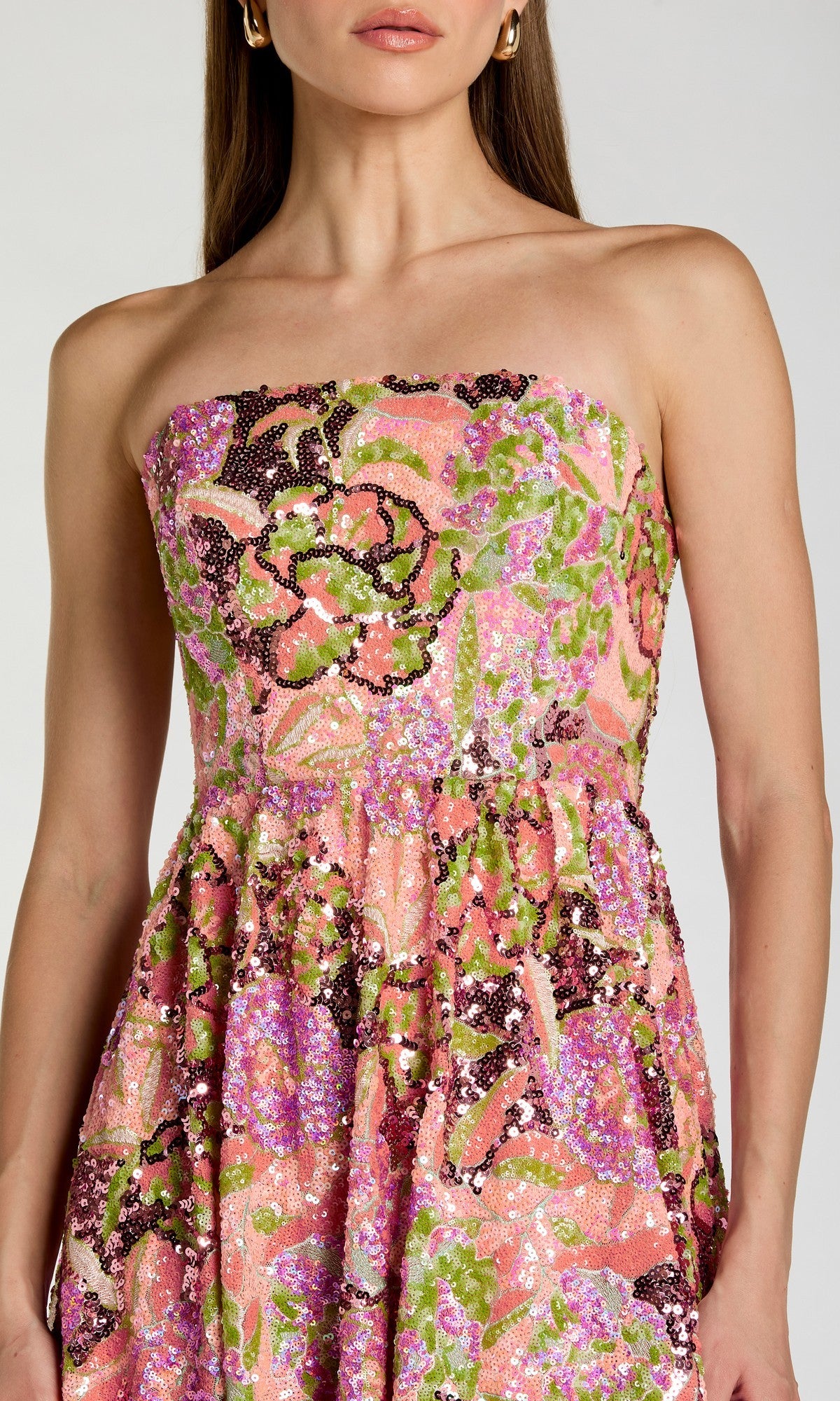 A woman wearing the Mac Duggal 56386 Tea-Length Party Dress, which features a strapless design and a vibrant floral and abstract pattern in pink, green, and orange tones.