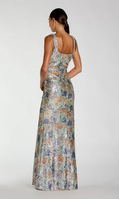 A woman stands with her back turned, wearing the Mac Duggal 56388 long formal dress—a sleeveless, floor-length gown adorned with multicolored sequins, a square back neckline, and delicate floral embellishments.