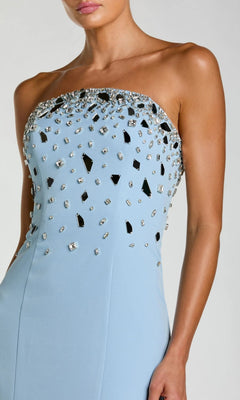 A woman wears the Mac Duggal 56393 long formal dress, a strapless mermaid gown in light blue, featuring a bodice embellished with an array of silver and mirrored accents that capture the timeless elegance of Mac Duggal design.