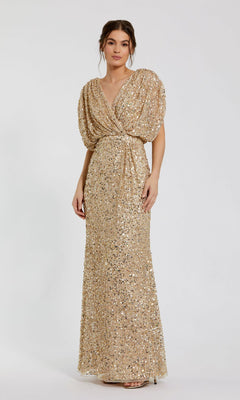 A woman stands against a plain white background wearing the Mac Duggal 5640: a floor-length gold sequin formal dress with short sleeves and a gathered waist.
