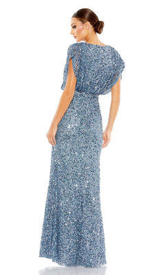 A woman in a Mac Duggal 5640 Short Sleeve Long Sequin Formal Dress stands facing away, glancing over her shoulder, with her hair styled in a low bun.