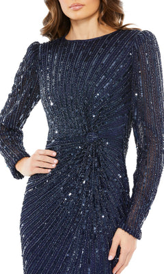A woman wears the Mac Duggal 5641 long-sleeve sequin formal dress, showcasing navy blue sequins, a fitted waist, and a textured diagonal pattern; her face is partially out of frame.