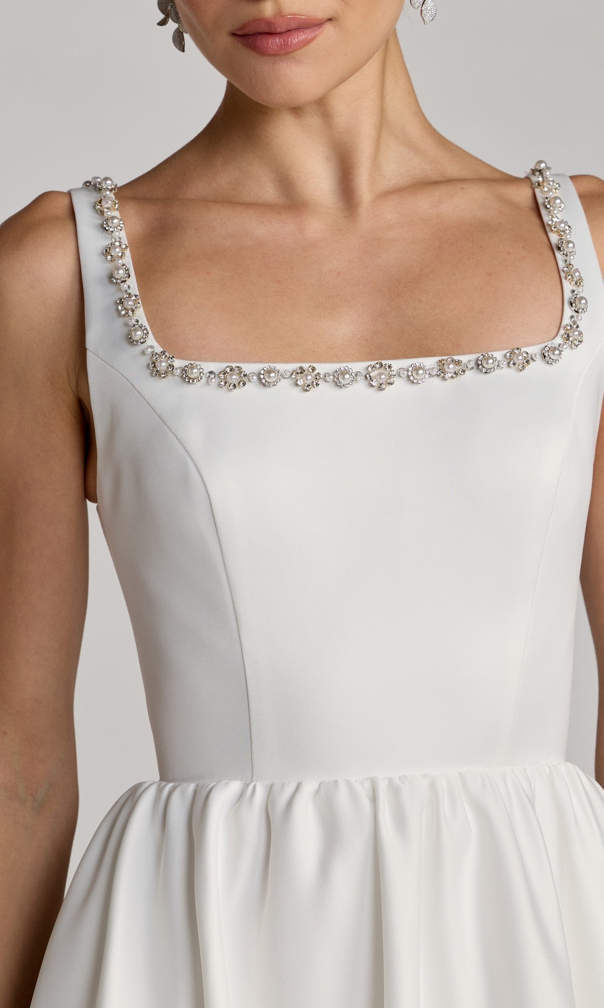 Woman wearing the Mac Duggal 56417 Tea-Length Party Dress, a sleeveless white satin design featuring a square neckline adorned with small crystals, shown from shoulders to waist.