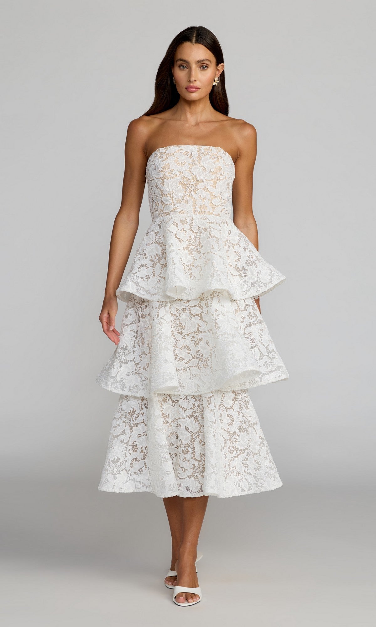 A woman models the Tea-Length Party Dress: Mac Duggal 56419 in ivory—a strapless lace design featuring a ruffled A-line skirt that falls to mid-calf—paired with white heels against a plain light gray background.