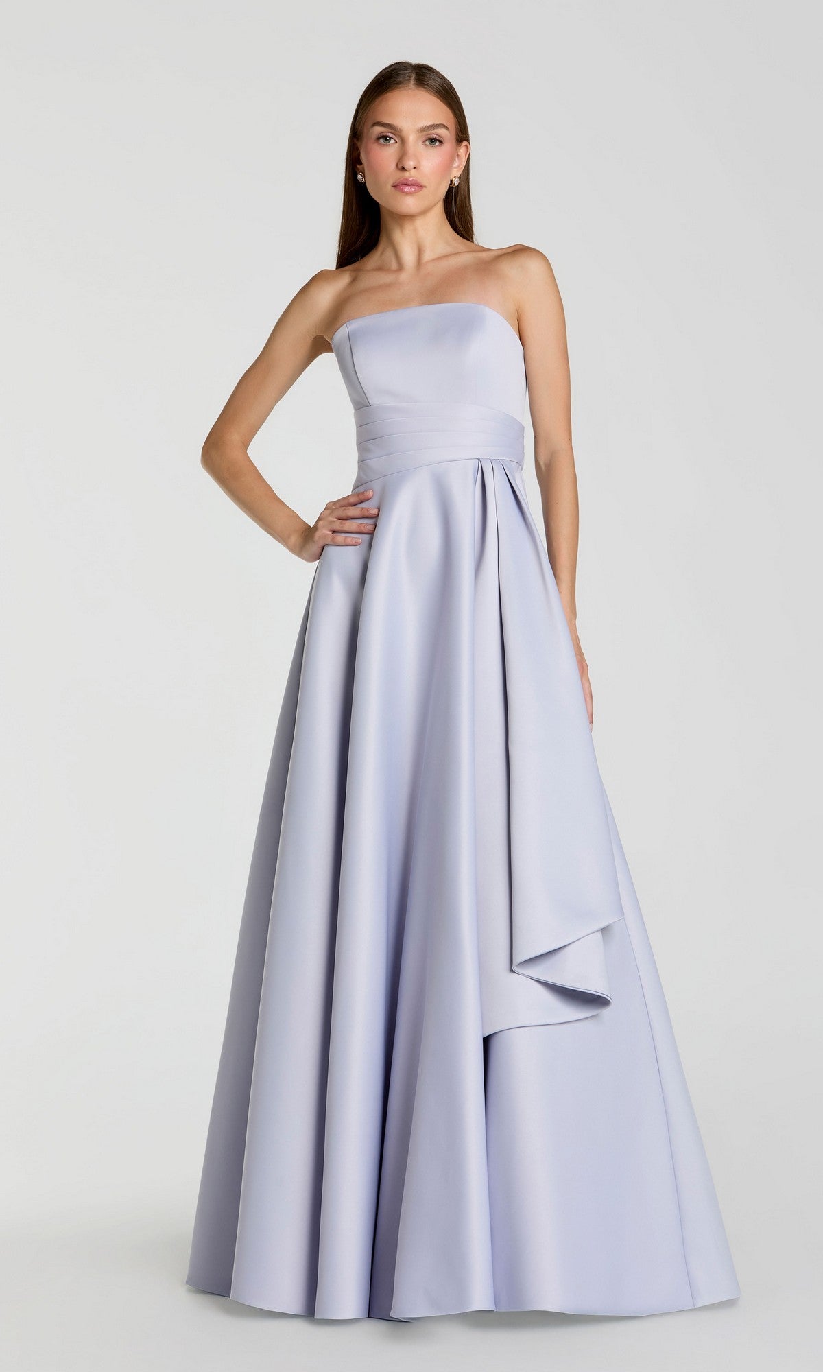 A woman wearing the Mac Duggal 56425 Long Formal Dress—a strapless, floor-length gown in periwinkle with a minimalistic design and draped waist detail—stands against a plain light background.