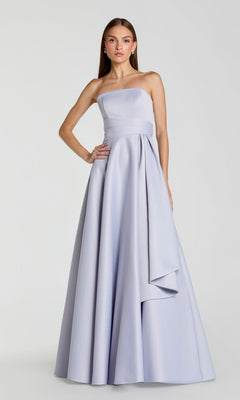 A woman wearing the Mac Duggal 56425 Long Formal Dress—a strapless, floor-length gown in periwinkle with a minimalistic design and draped waist detail—stands against a plain light background.