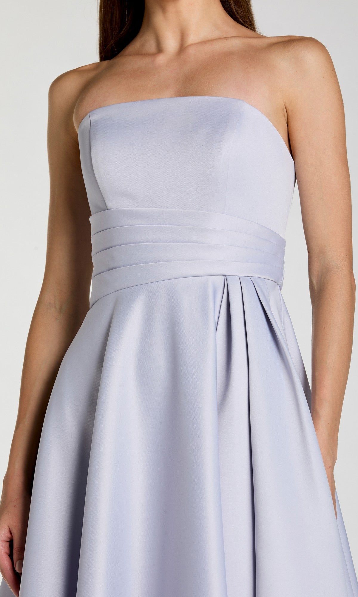 A woman wearing the Long Formal Dress: Mac Duggal 56425—a strapless, light lavender satin gown featuring a fitted bodice and pleated waistband—embodies the elegance of minimalist evening wear.