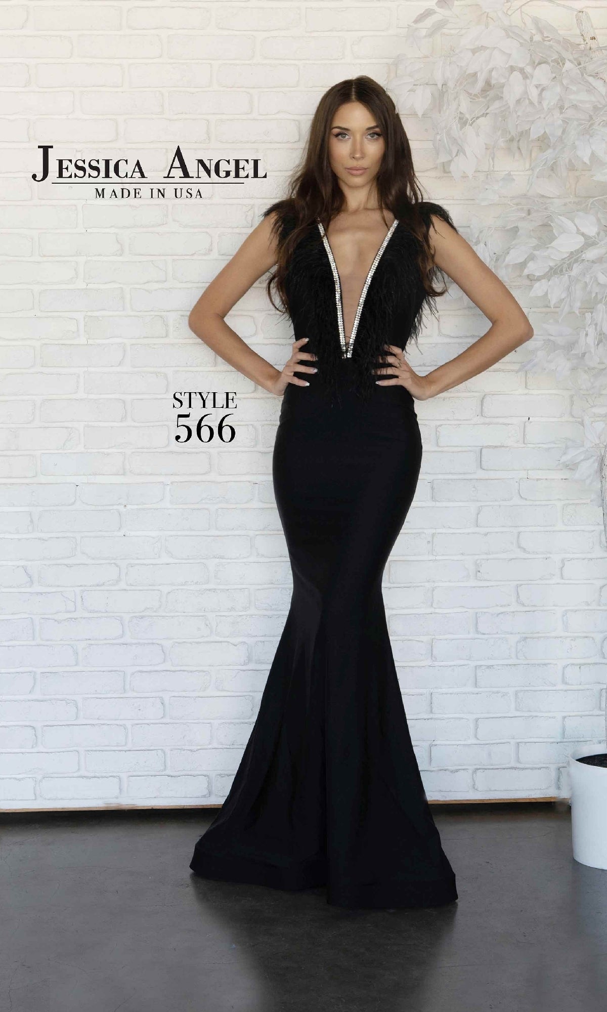 A woman stands against a white brick wall, wearing the Feather-Trimmed Long Formal Dress: Jessica Angel 566, a sleeveless formal gown with a deep plunging v-neck. 
