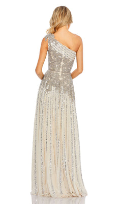 A woman faces away, wearing the Beaded Long Silver Prom Gown: Mac Duggal 5679—a floor-length, one-shoulder dress with sequin embellishments and a beige sheer overlay.