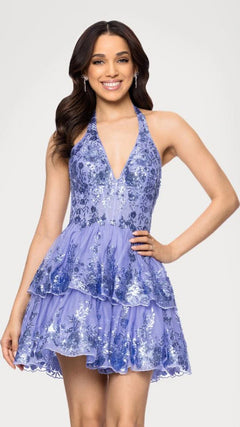 A woman wearing the Short Prom Dress: Blondie Nites 5702BN in periwinkle, a sleeveless fit-and-flare style with floral patterns and subtle sequin details, stands smiling against a plain background.