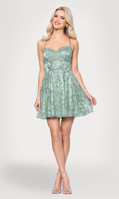 A woman in a Blondie Nites 5705BN Mini Green Sequin Hoco Dress, junior size, knee-length with spaghetti straps, pairs it with silver high-heeled sandals and stands against a white background.