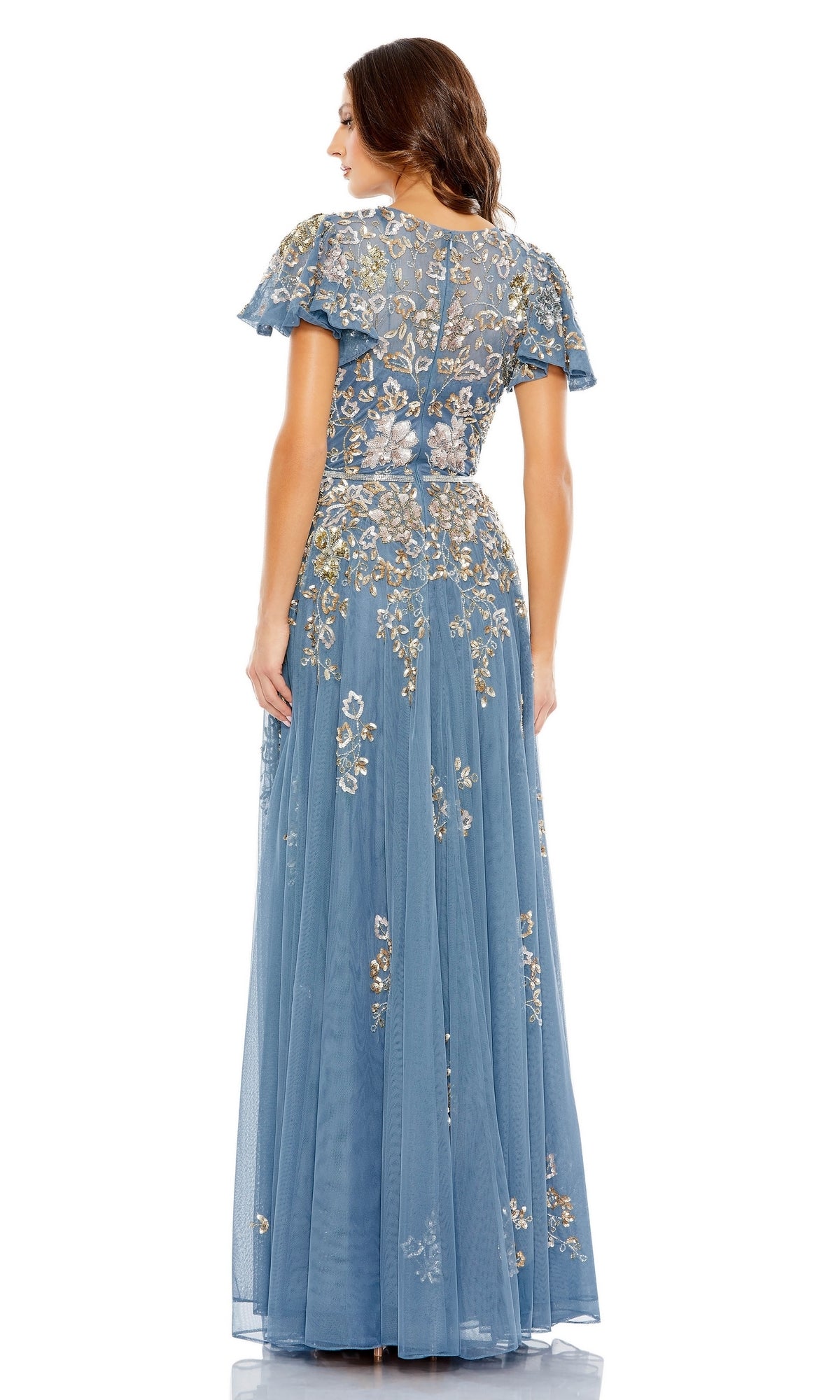 Woman wearing the Mac Duggal 5717 Short Sleeve Beaded Formal Dress, a blue floor-length gown with floral embroidery and sheer overlay, shown from the back against a white background.