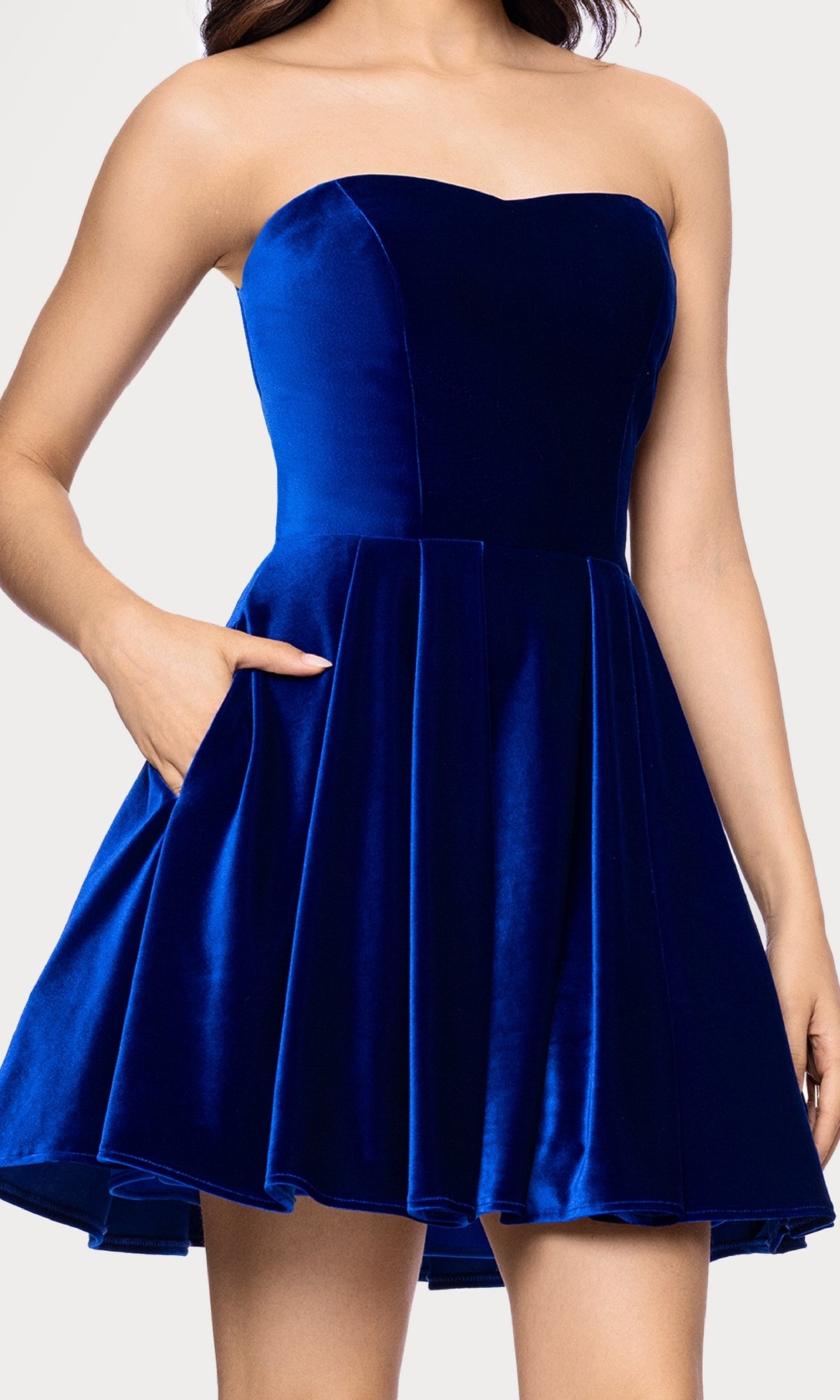 A woman wears the Short Velvet Hoco Dress: Blondie Nites 5718BN—an affordable, strapless royal blue velvet fit-and-flare cocktail dress with a sweetheart neckline and side pockets.