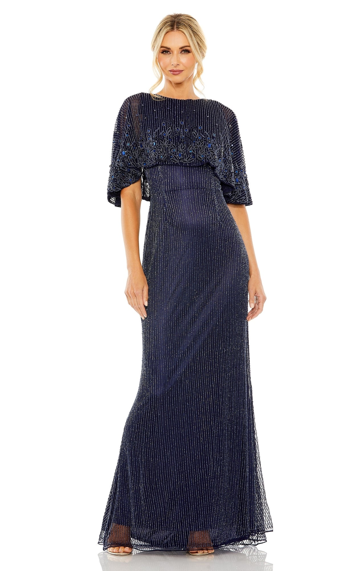A woman wears the Mac Duggal 5797 Midnight Blue Beaded Formal Gown, featuring a floor-length silhouette, vertical beaded details, and a sheer embellished overlay—an elegant pick for the mother of the bride.