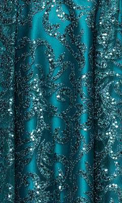Close-up of the Mini Teal Glitter Hoco Dress Blondie Nites 5802BN, showcasing teal fabric adorned with swirling sequin and glitter patterns for a shiny, textured decorative surface.