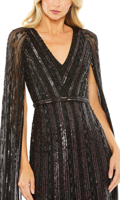 Woman wearing the Long Formal Dress 5915 by Mac Duggal—a black sequin gown with a V-neckline and sheer, embellished cape sleeves—shown from shoulders to mid-thigh.