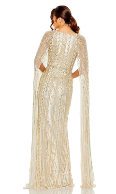 A woman models the Long Formal Dress 5915 by Mac Duggal, featuring gold and white sequins, a floor-length cape, sheer embellished sleeves, and an elegant v-neckline and back, standing against a white background.
