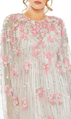 A woman wears the Mac Duggal 5917 Beaded-Cape Short Hoco Dress, featuring a sheer cape over a pink and white dress adorned with 3D floral and butterfly appliqués and vertical sequined stripes for a modern cocktail look.