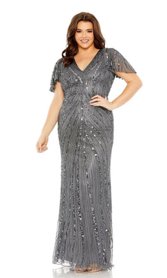 A woman smiles against a white background wearing the Long Plus-Size Prom Dress 5945 by Mac Duggal, a floor-length, short-sleeve silver sequin evening gown.