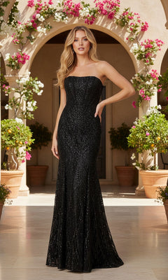 A woman stands outside before an arched doorway, surrounded by potted plants and flowers, wearing a strapless black glitter prom dress—Blondie Nites 5955BN—with a subtle pattern.