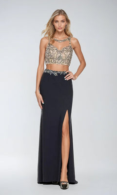 A woman wearing the Juliet 595 Long Prom Dress, featuring a beaded sleeveless crop top and a black skirt with a side leg slit, stands against a plain light background.