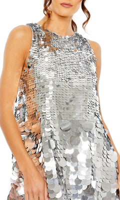 A woman wearing the Short Homecoming Dress 5961 by Mac Duggal—a sleeveless, silver sequin A-line party dress adorned with large, reflective paillettes.