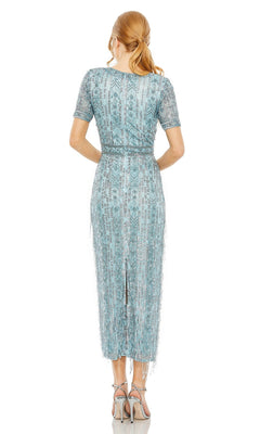 A woman with light brown hair in a ponytail wears the Mac Duggal 5980 Midi Fringe Wedding-Guest Dress and high-heeled sandals, shown from behind against a white background.