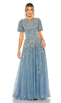 A woman wears the Mac Duggal 5991 Short Sleeve Beaded Formal Dress in blue, featuring intricate silver embroidery and a sheer overlay, standing against a white background.