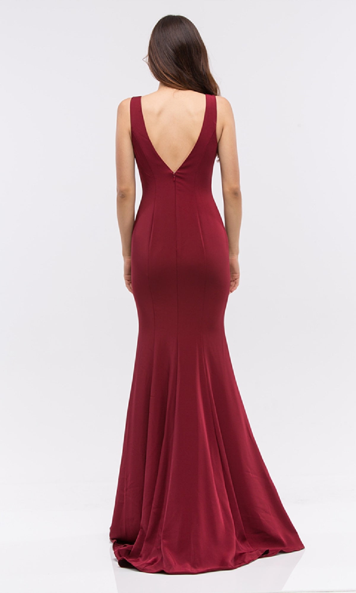 A woman in the Classic Long V-Neck Satin Prom Dress: Eureka 6010, a sleeveless, floor-length burgundy gown with a deep V-back, stands facing away against a plain white background.