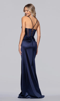 A woman wearing the Blondie Nites 6014BN long navy satin prom dress with spaghetti straps, lace-up back, and floor-length skirt stands looking over her shoulder against a plain background.