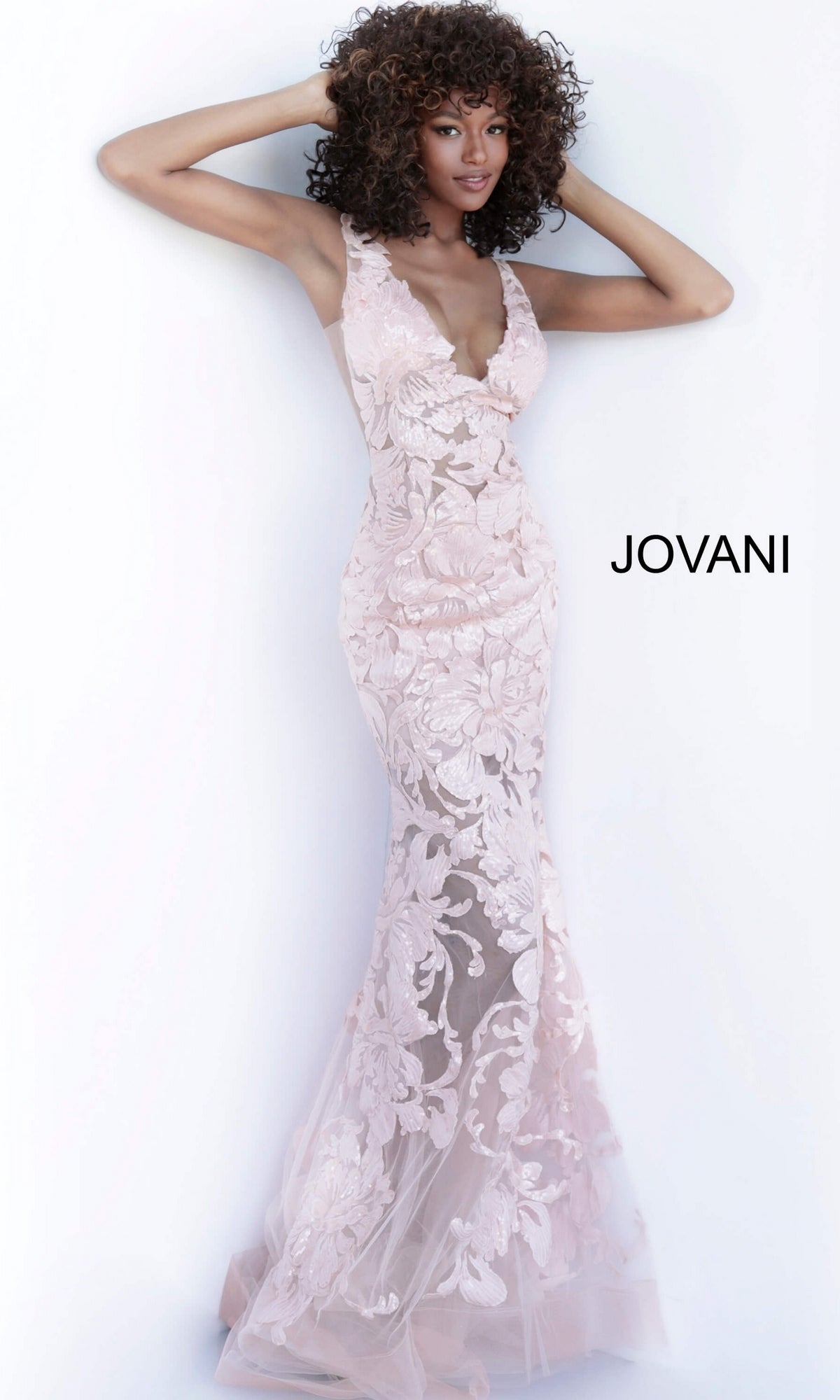 A person wears a pale pink Jovani Embroidered Long Prom Dress with Sequins, featuring a floor-length mermaid silhouette, V-neckline, and floral embroidery.