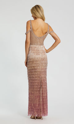 A woman stands facing away, wearing the Mac Duggal 6032 Fringed Pink Ombre Formal Dress with layered fringe in gradient beige to mauve and an open back.