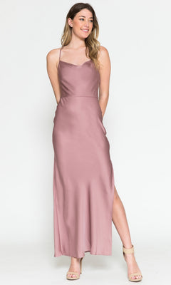 A woman wearing the Cowl-Neck Simple Tea-Length Satin Dress 6115 with a side slit and nude heels stands against a plain white background.