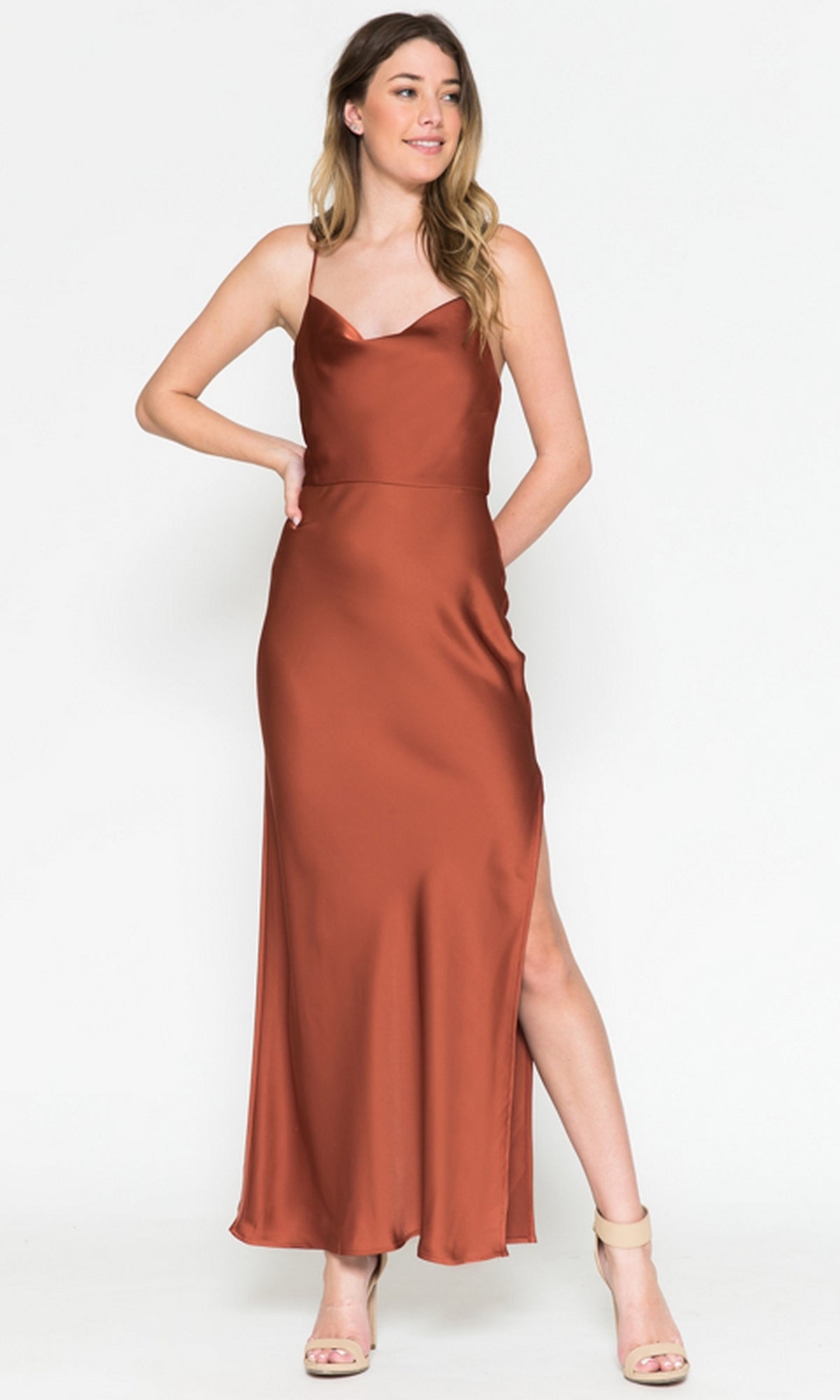 Woman wearing the Cowl-Neck Simple Tea-Length Satin Dress 6115 by Amelia Couture in rust, sleeveless with a side slit, one hand on her hip and the other by her side.