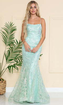 A woman stands indoors near a green potted plant, wearing the Iridescent Long Embellished Prom Dress 6116—a light blue, floor-length gown with thin straps and sequin details.