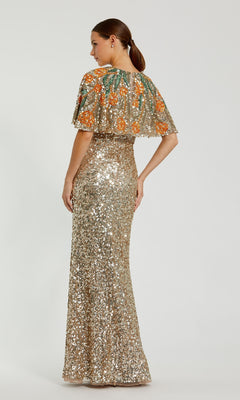 A woman stands with her back to the camera in the Caped Gold Sequin Formal Gown: Mac Duggal 6120, featuring a long gold sequin dress and a short embroidered cape with orange floral designs—perfect for mothers of the bride.