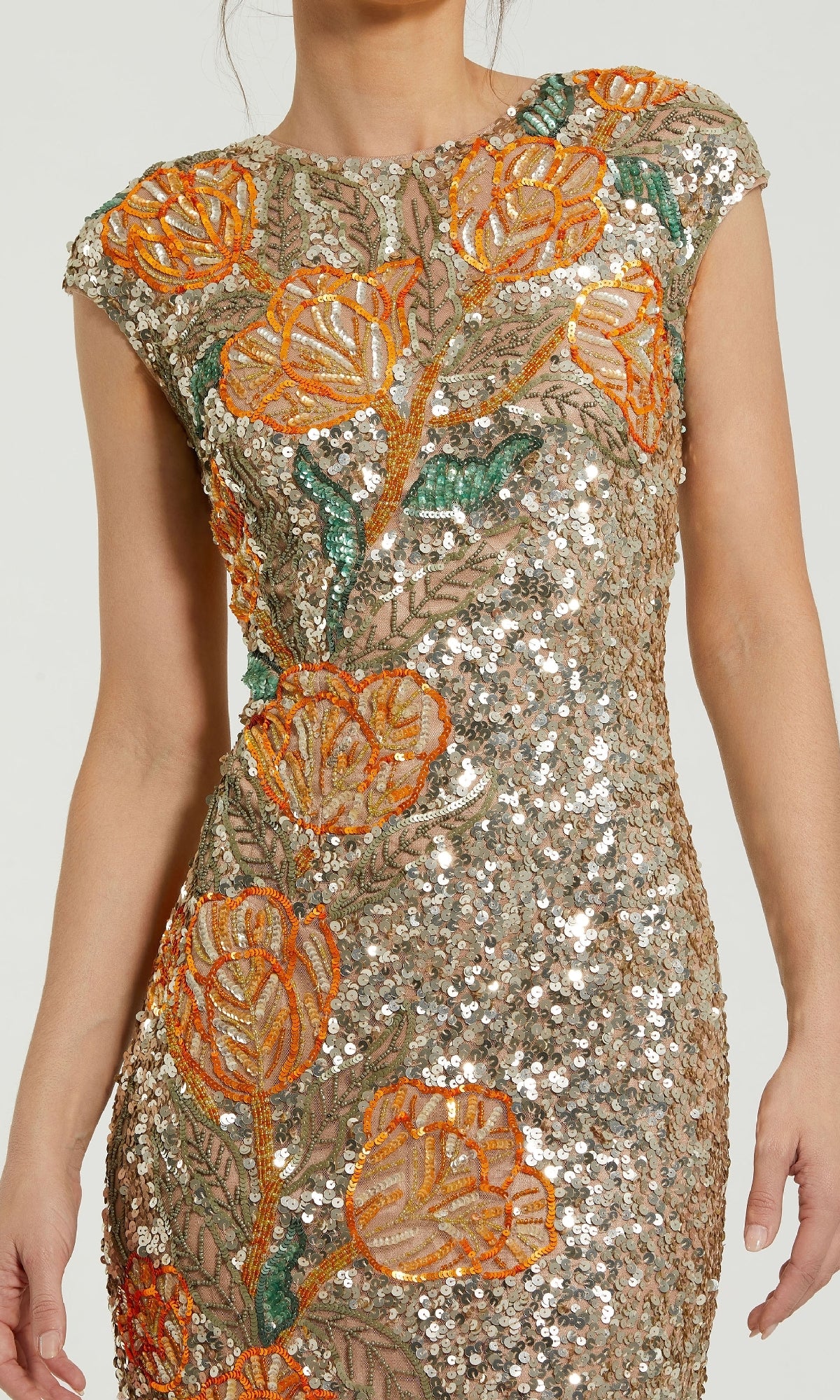 A woman wearing the Mac Duggal 6121 long formal dress, featuring orange and green floral embroidery with sequin embellishments on a beige mesh background.
