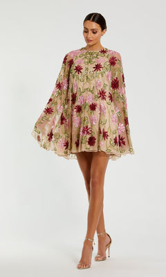 A woman wears the Mac Duggal 6123 Sequin Short Wedding Guest Dress, a beige loose-fit style with pink and red floral embroidery, paired with nude heels against a plain background—ideal as a sequin floral party dress.