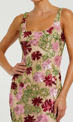 A woman poses with one hand on her hip in the Mac Duggal 6124 Beaded Midi Wedding Guest Dress, a sleeveless nude dress adorned with pink and red floral sequin embroidery.