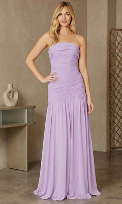 A woman with light wavy hair smiles slightly indoors while wearing the Amelia Couture 6132 Long Prom Dress in lilac, featuring a strapless neckline, floor-length silhouette, and figure-flattering ruching.