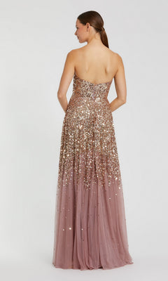 A woman stands with her back to the camera, modeling the Mac Duggal 6144 long formal dress—a strapless gown adorned with rose gold ombre sequins on the bodice and a sheer, floor-length tulle skirt.