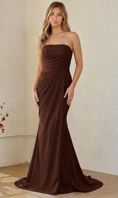 A woman in a brown Long Formal Dress: Amelia Couture 6149 with strapless, draped detailing stands indoors against a plain background.