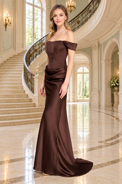 A woman stands in a grand foyer wearing a brown, floor-length, off-the-shoulder Amelia Couture 6151 gown with a corset-style bodice.