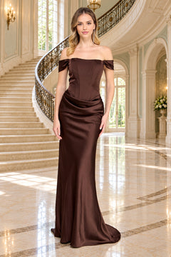 A woman wearing an Amelia Couture 6151 floor-length, off-the-shoulder brown satin gown with a corset-style bodice.